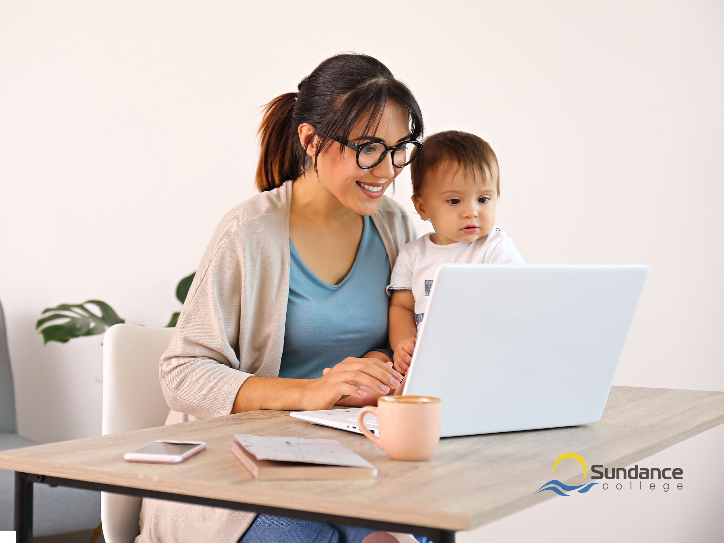 Mother attending an online meeting while child sits beside her