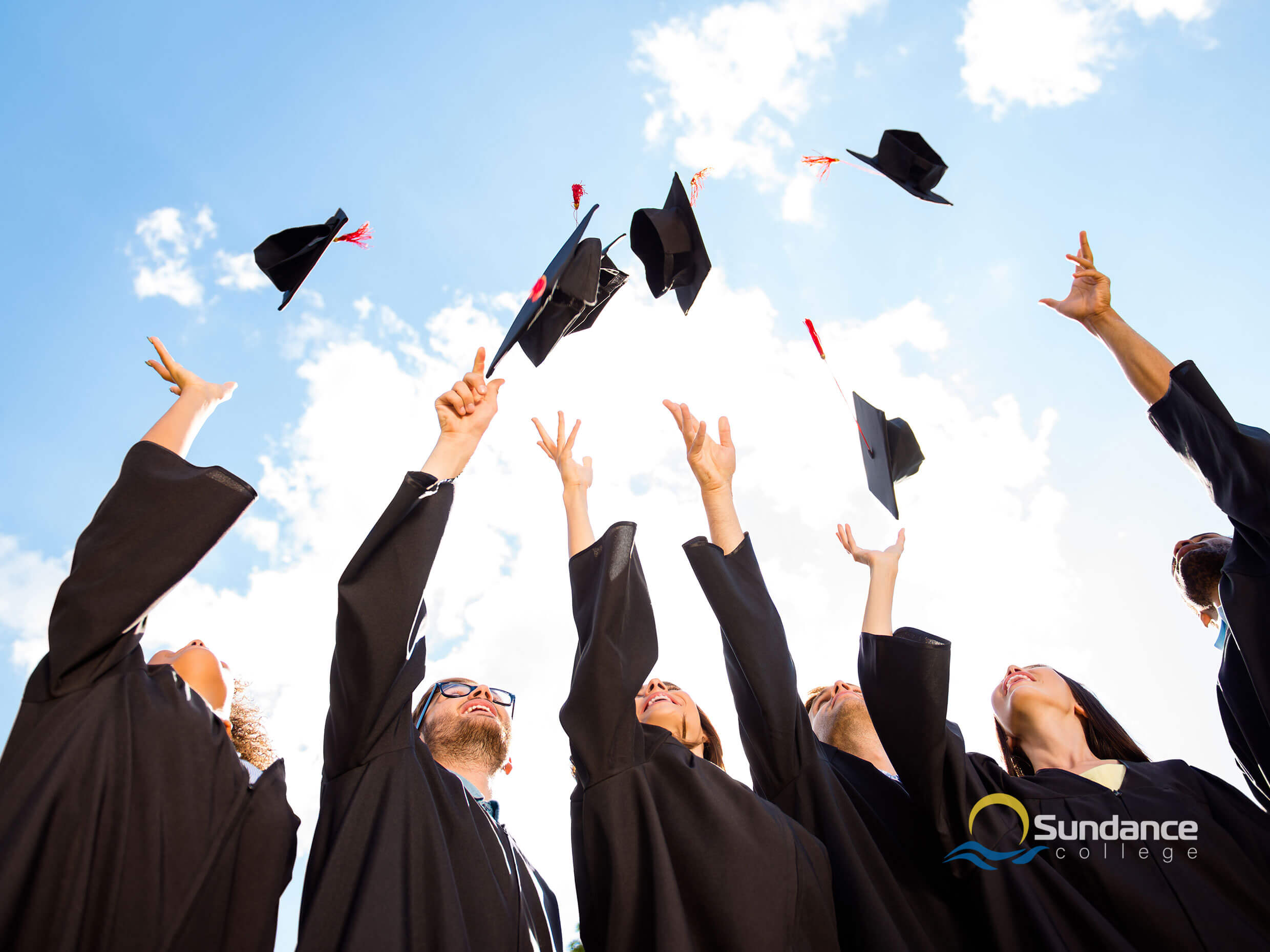 general business management diploma graduating class, throwing caps into the air with a blue sky overhead, celebrating the conclusion of their courses
