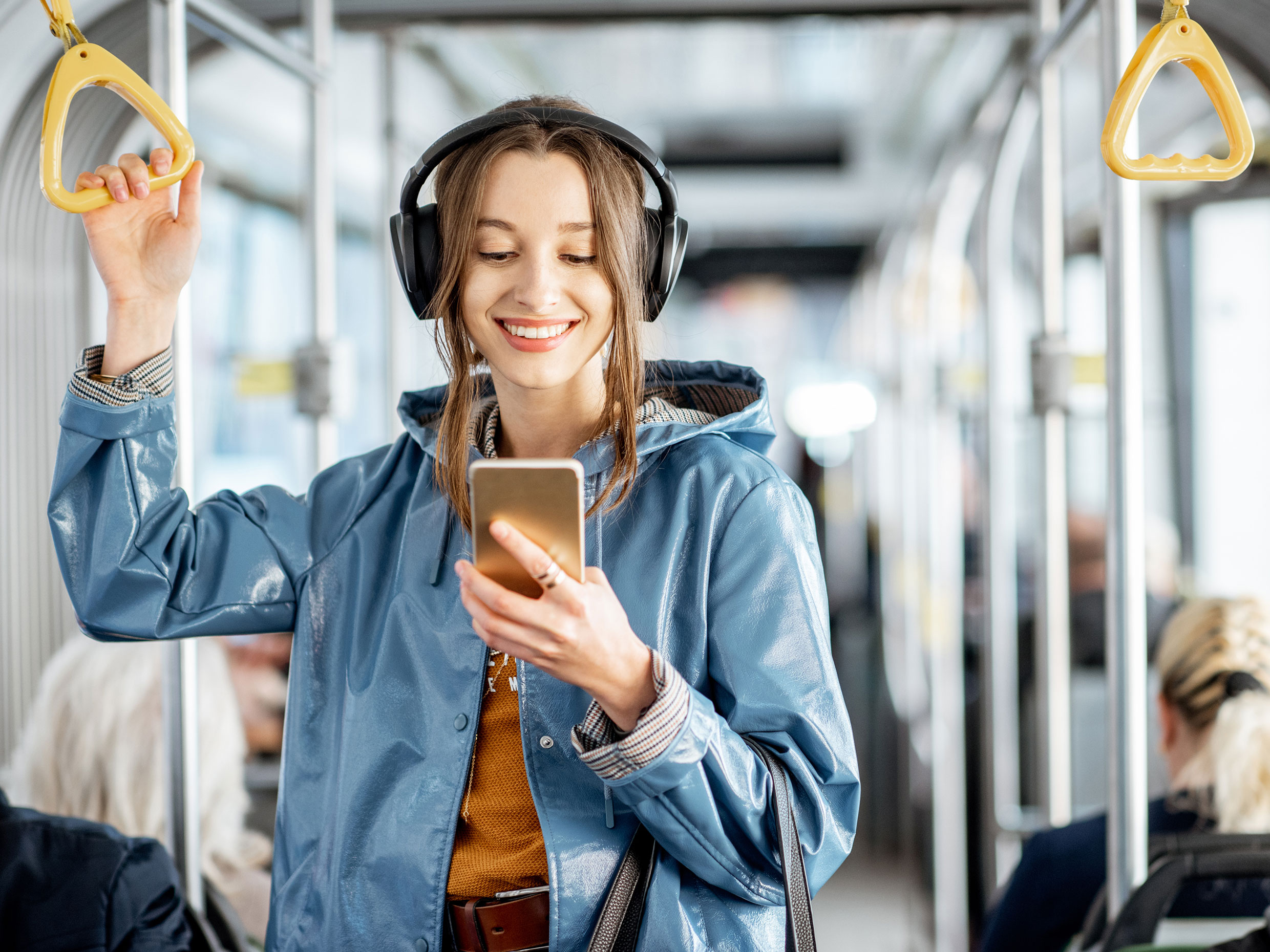 Student with headphones completing assignment on phone while riding public transport.
