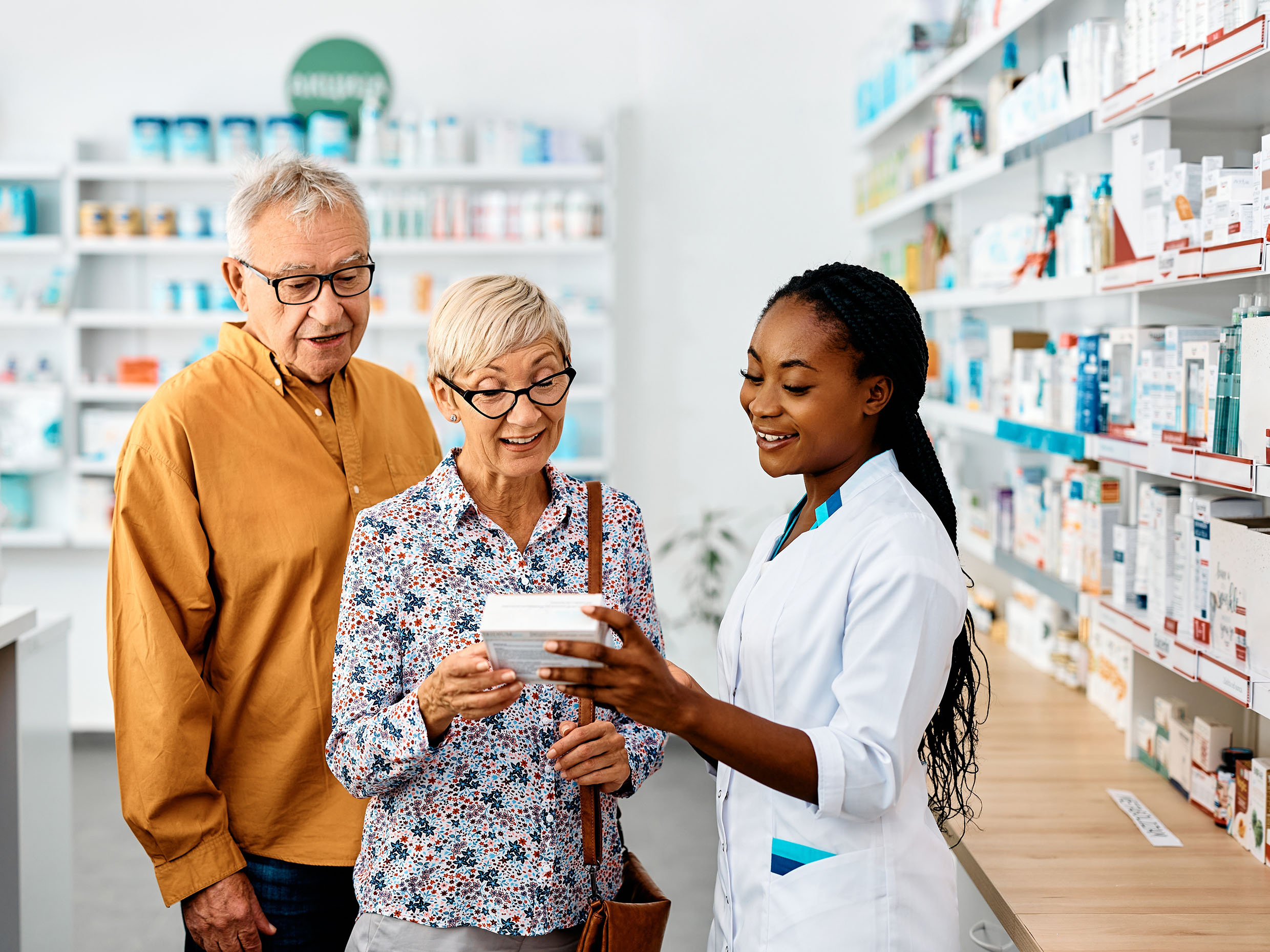 A happy female pharmacy assistant helping seniors in a community drugstore.