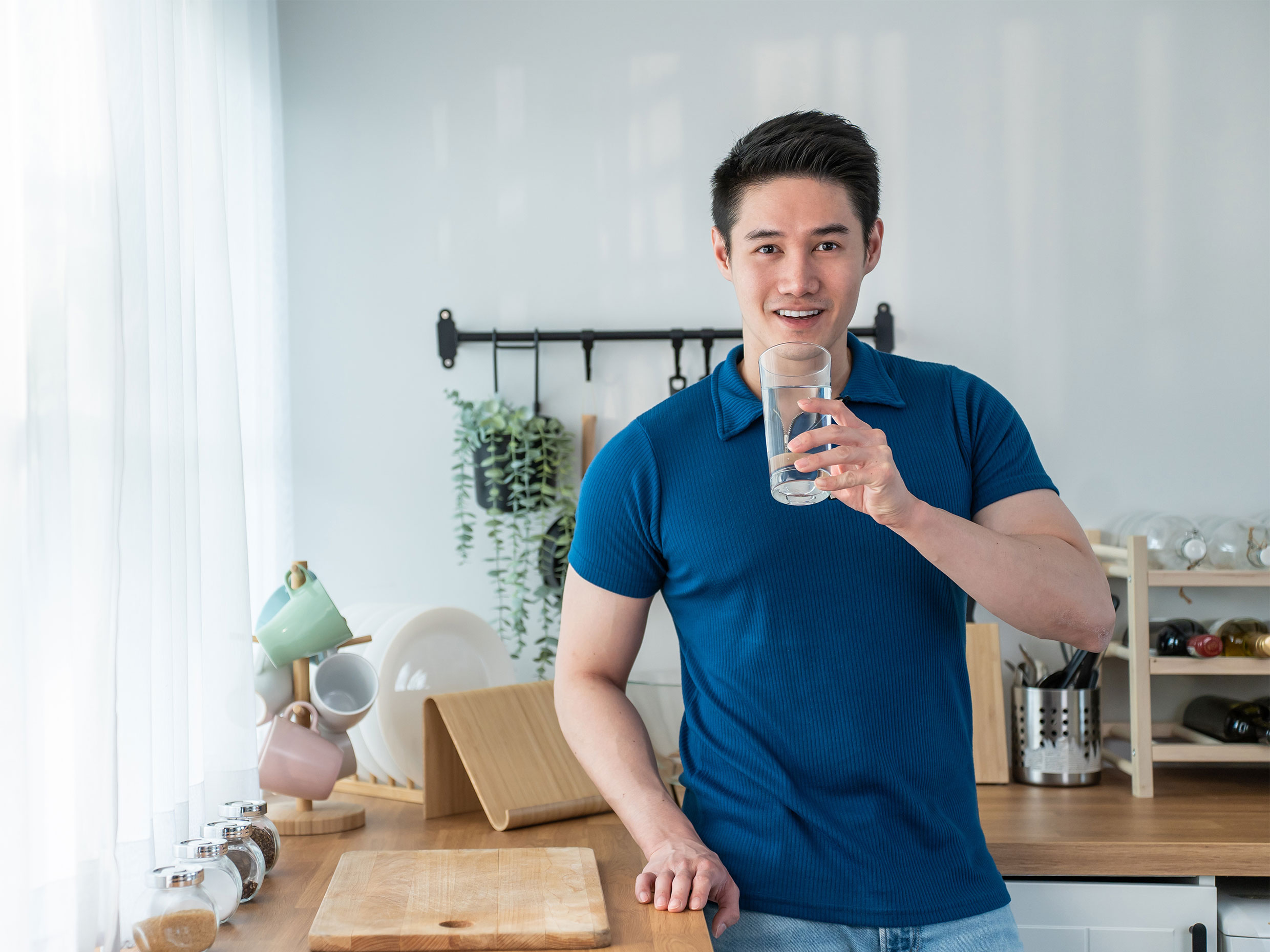 man in the kitchen confidently looking at camera with a glass of water.