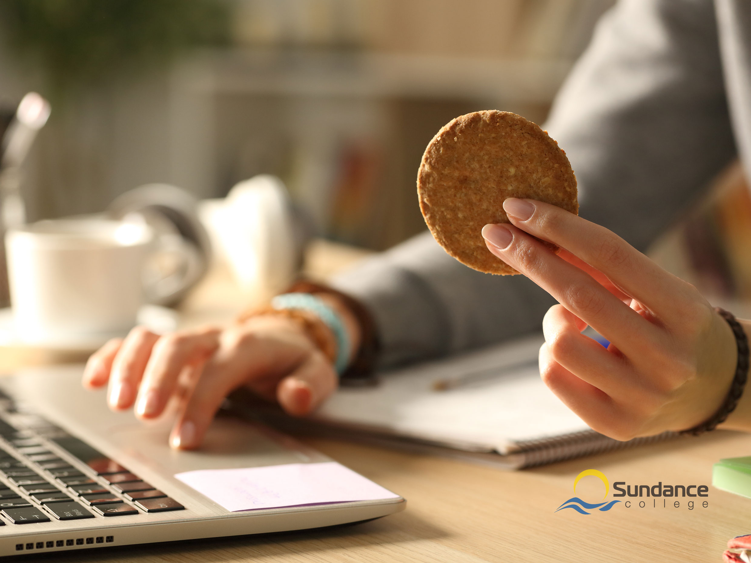 Student enjoying cookie while studying online