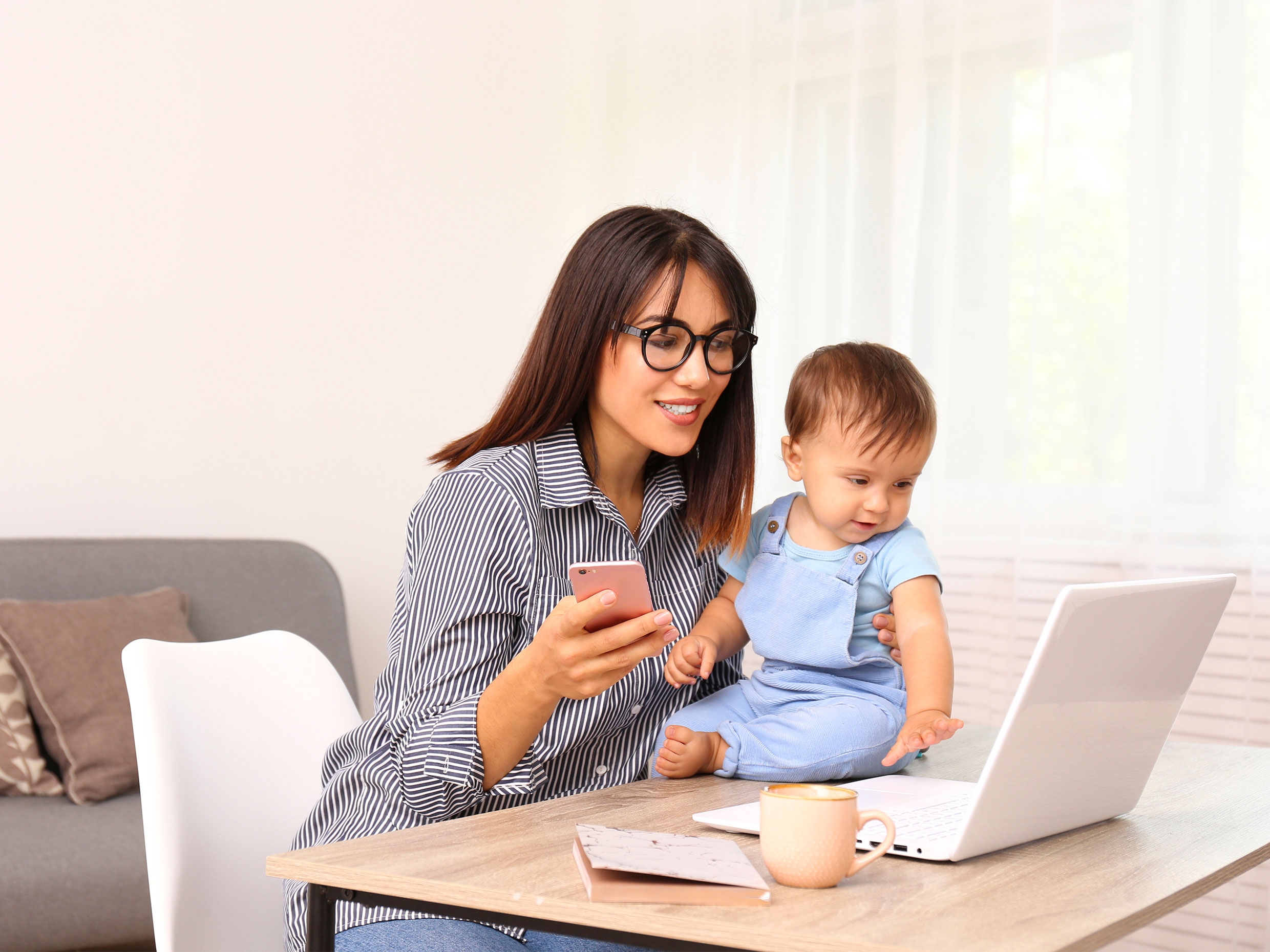 Mother with young child sitting in front of laptop.