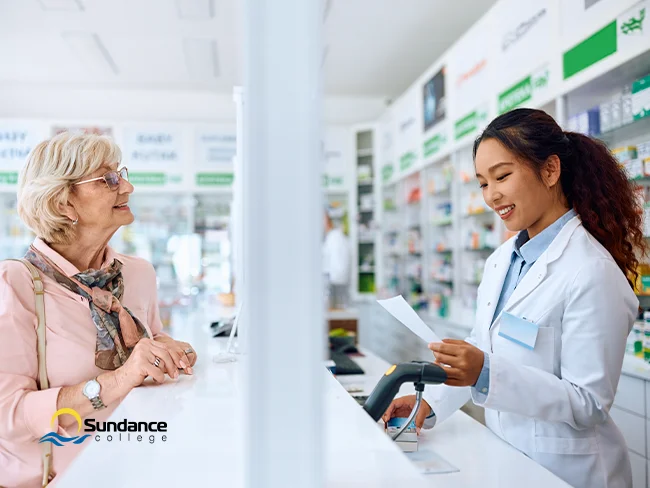 Pharmacy assistant helping an elderly woman at the counter in a pharmacy.