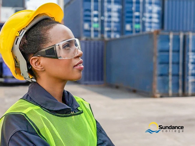 Woman wearing safety gear looking up while working a supply chain management job.