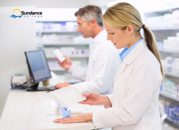 Pharmacy assistant helps pharmacist fill prescription at counter 