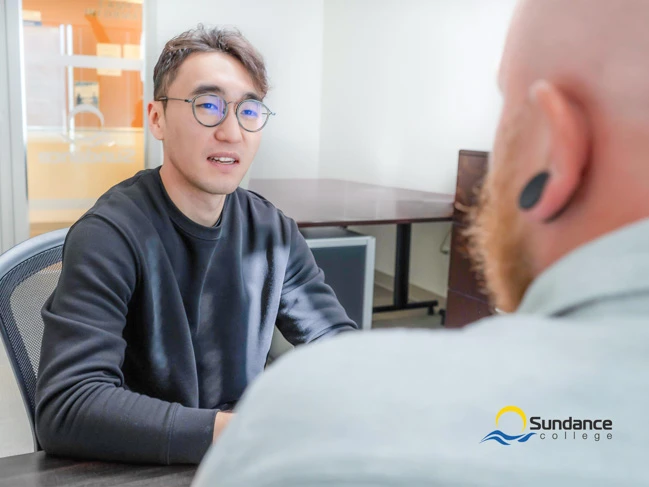 A Sundance College student sitting in front of his instructor getting assistance on his home assignment in the Calgary campus.