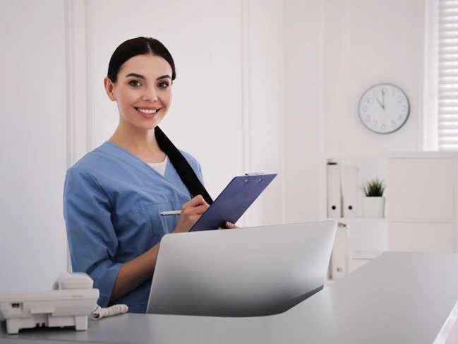 a woman in blue scrubs holding a clipboard