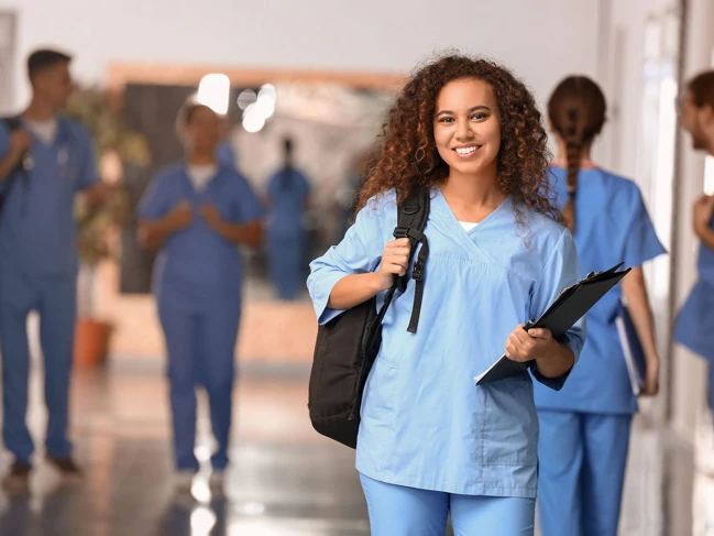 a woman in blue scrubs holding a clipboard and a backpack