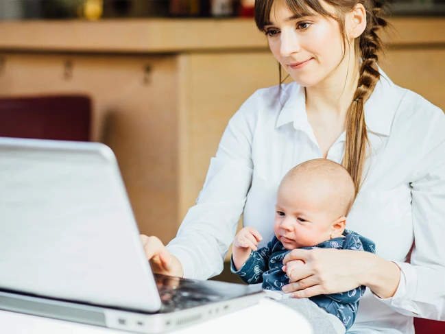 mother studying online with child in her lap