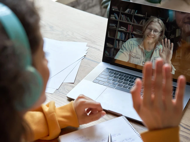 a woman in headphones talking to a man on a laptop