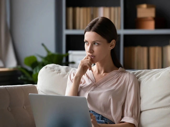 a woman sitting on a couch with her hand on her chin