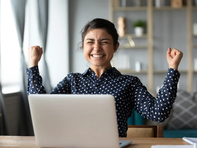 a woman sitting at a desk with her hands up