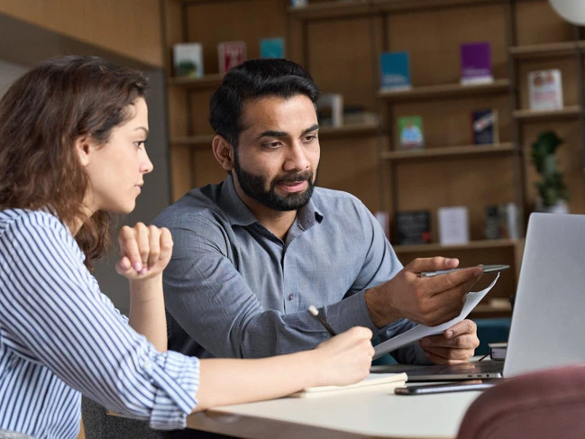 a man and a woman sitting in library searching for job in career services