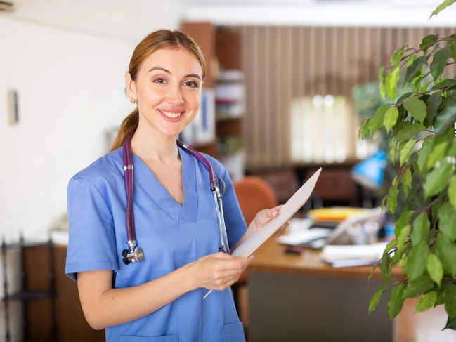 a woman in blue scrubs holding a clipboard