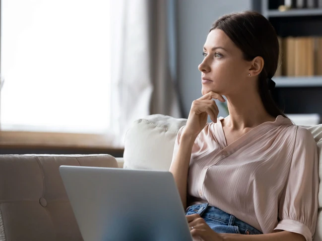 a woman sitting on a couch with her hand on her chin