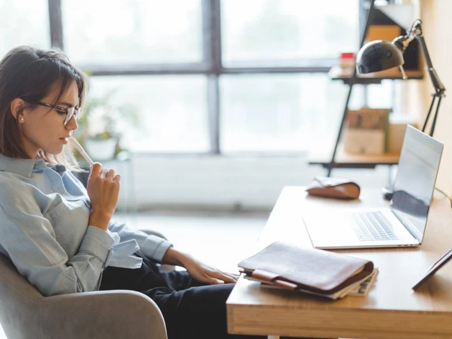 a woman sitting at a desk with a laptop online diploma college