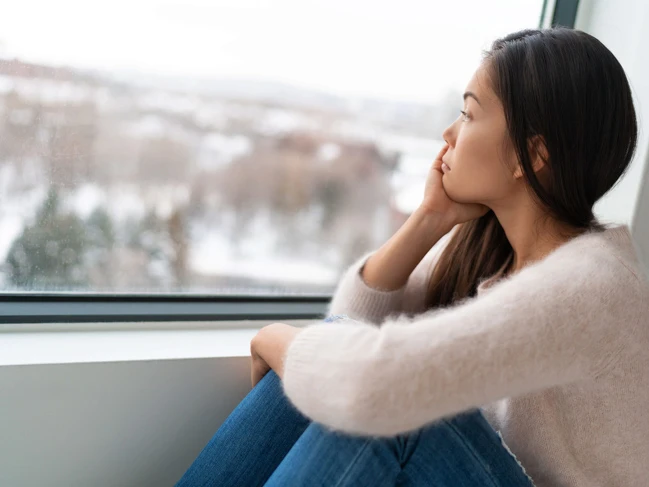 a woman sitting on a window sill looking out a window