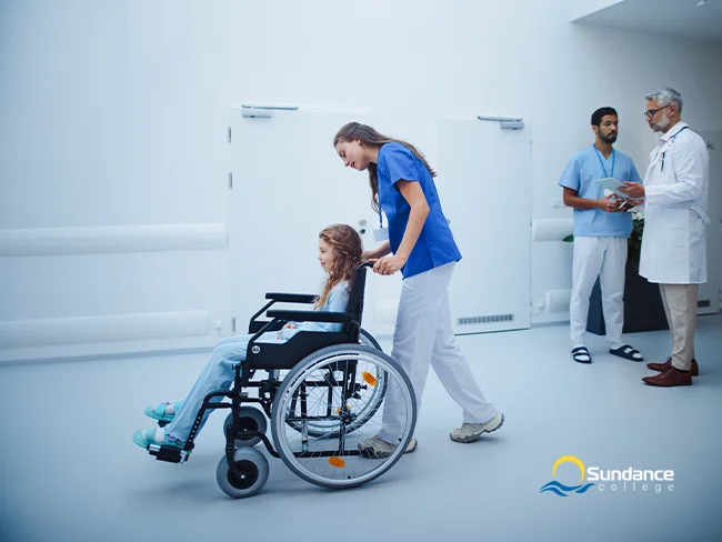 Numerous smiling personal support workers and other healthcare professionals stand in front of a medical setting.