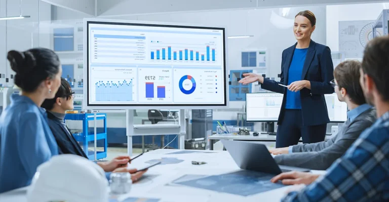 Female social media professional presenting a marketing strategy to her team in a modern glass-walled boardroom, engaging her colleagues with visual aids and data charts on the screen.