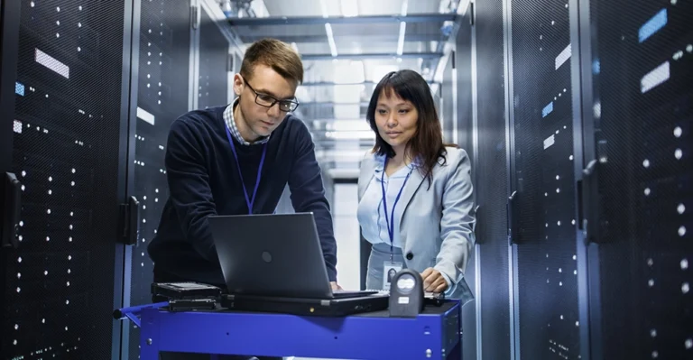 Two network systems professionals working together in a large data center.