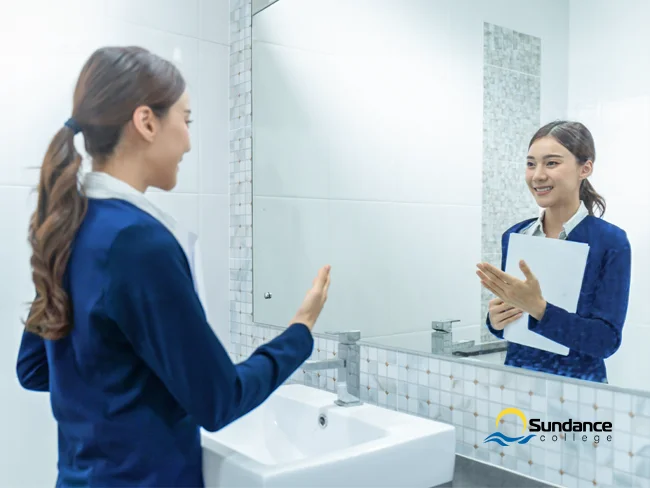 Female candidate practicing for an education assistant interview in front of a mirror.