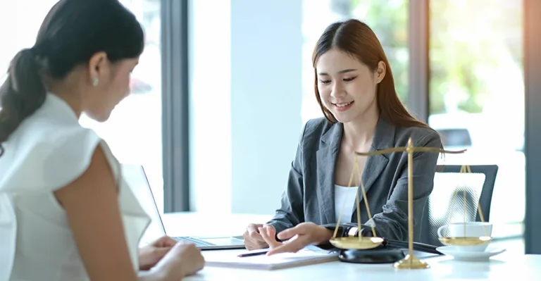 Legal assistant reviewing a document at her desk in a professional office setting.