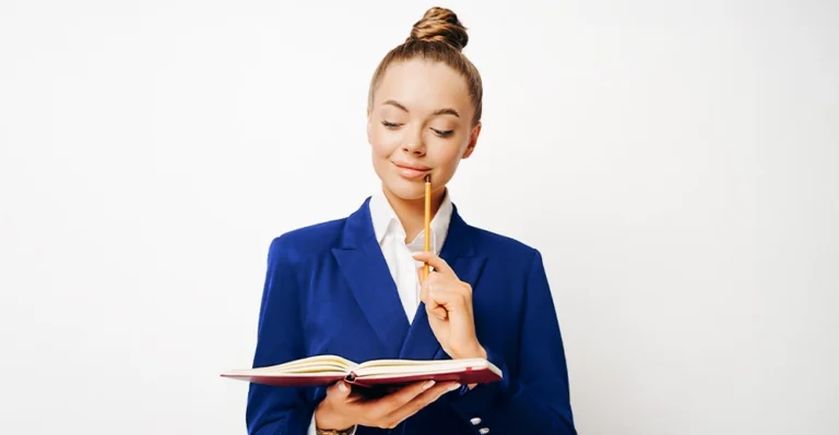 Woman in a black blazer holding a notebook and pencil, thoughtfully planning her career development plan.