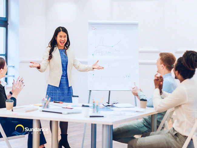 HR student leading an employee training session during her practicum, presenting data on a flip chart to a diverse group of professionals.
