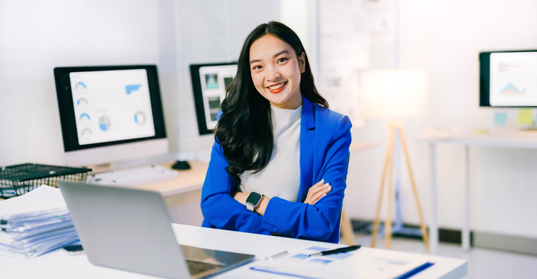 A young woman stands next to a laptop in a modern office, an example of becoming a digital marketer.