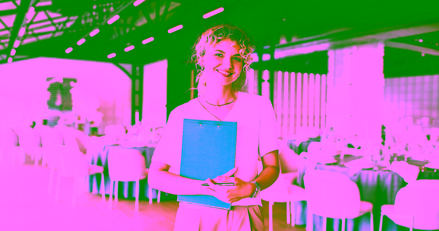 Woman holding clipboard in elegant event venue, likely an event planner.