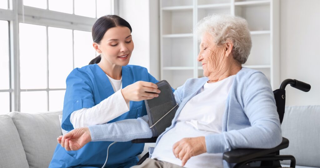 Home Support Worker assisting an older adult with a routine health checkup in a home setting.