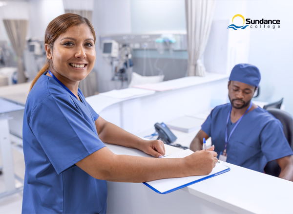 Hospital Unit Clerk updating information on a clipboard at a hospital reception area.