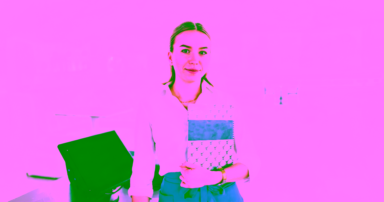 A woman stands at the front of a cafe holding a menu.
