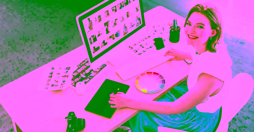 A graphic designer smiles as she sketches at her desk.