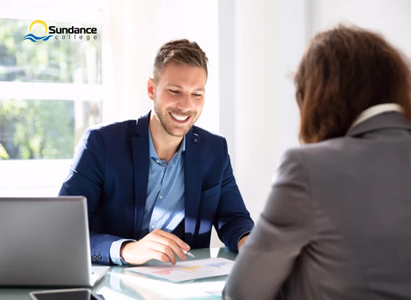 A male HR recruiter in suit sitting at a table with a woman in front of him.