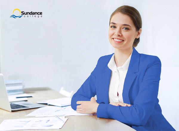 An accounting, tax, and payroll professional sits at her desk with a cup of coffee next to a laptop and financial documents.